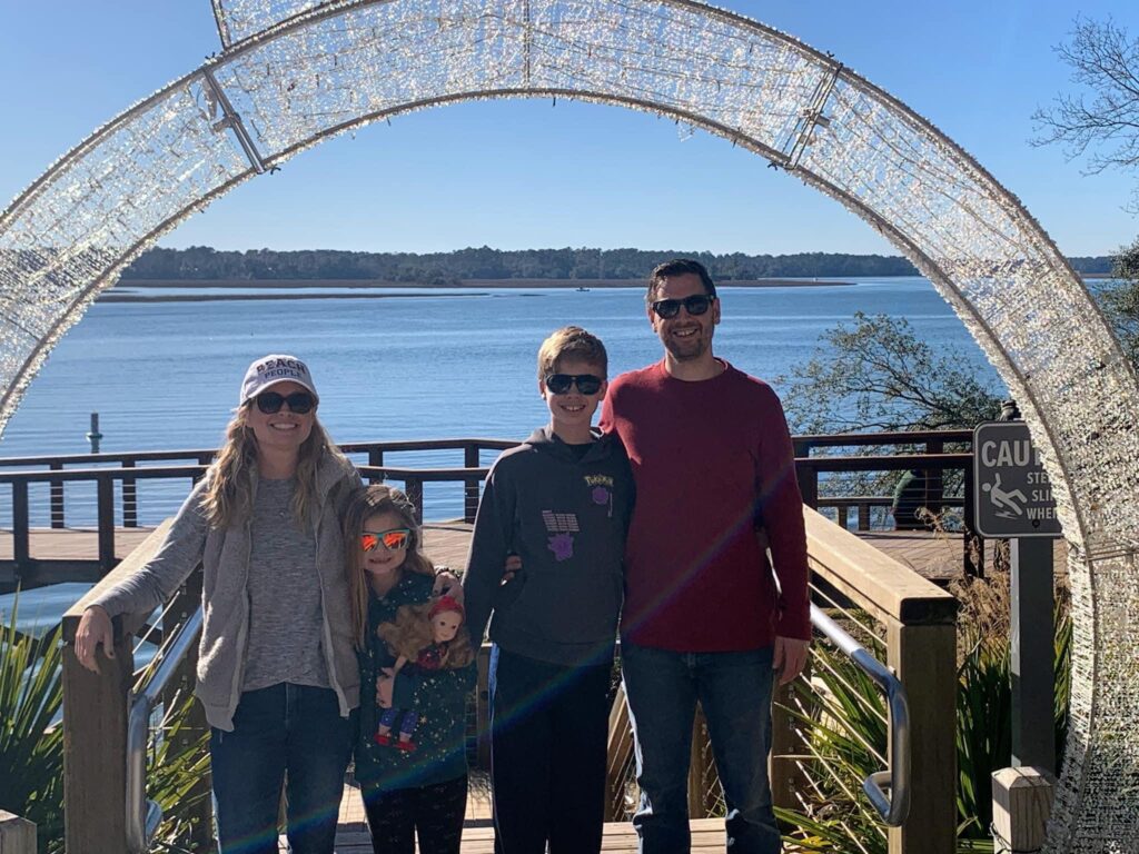 The Thompson family under Christmas arch with water in background