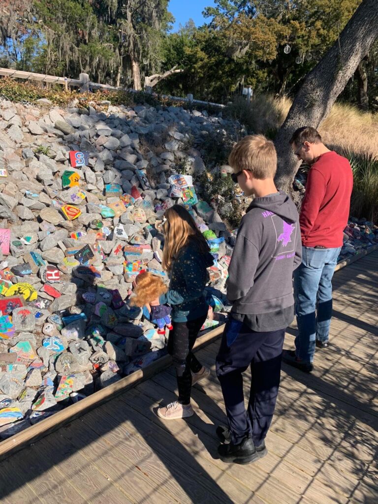 Matt and kids in front of large loose stones that have some painted