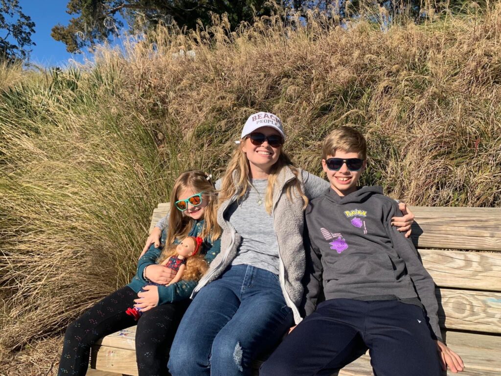 Amanda and kids sitting on bench with tall grass surrounding them