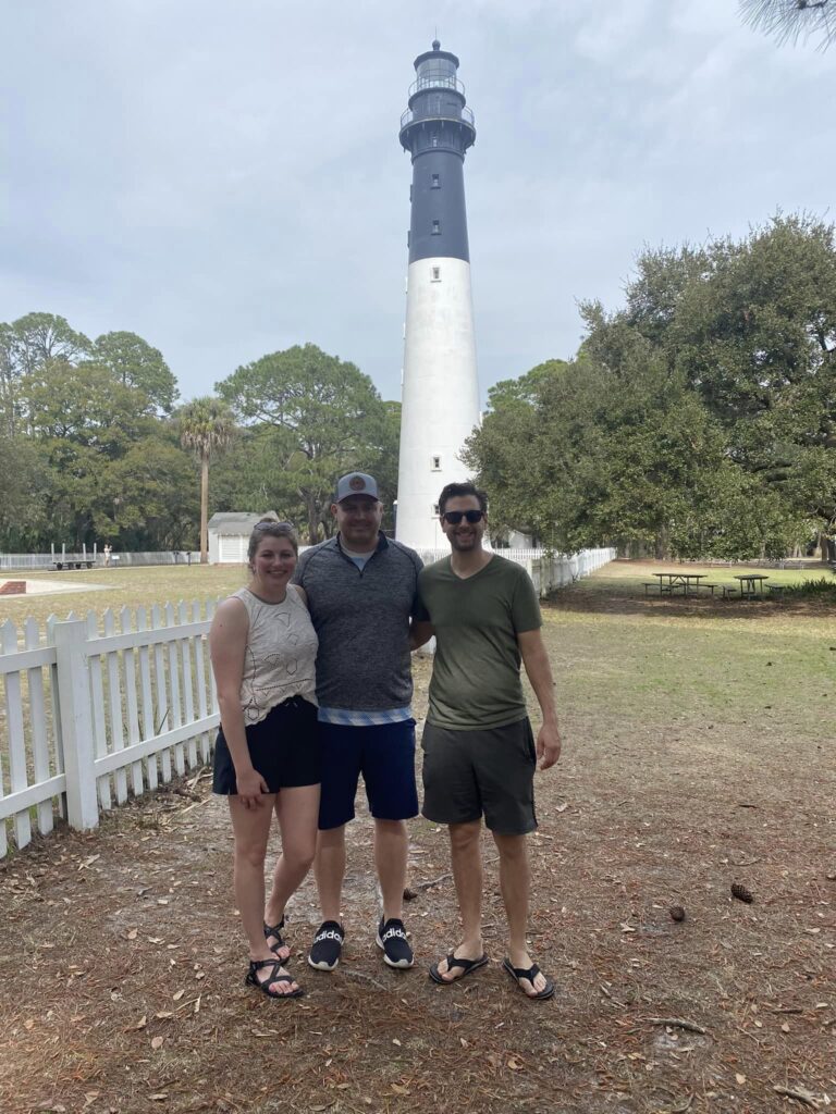 Three people standing in front of light house tower