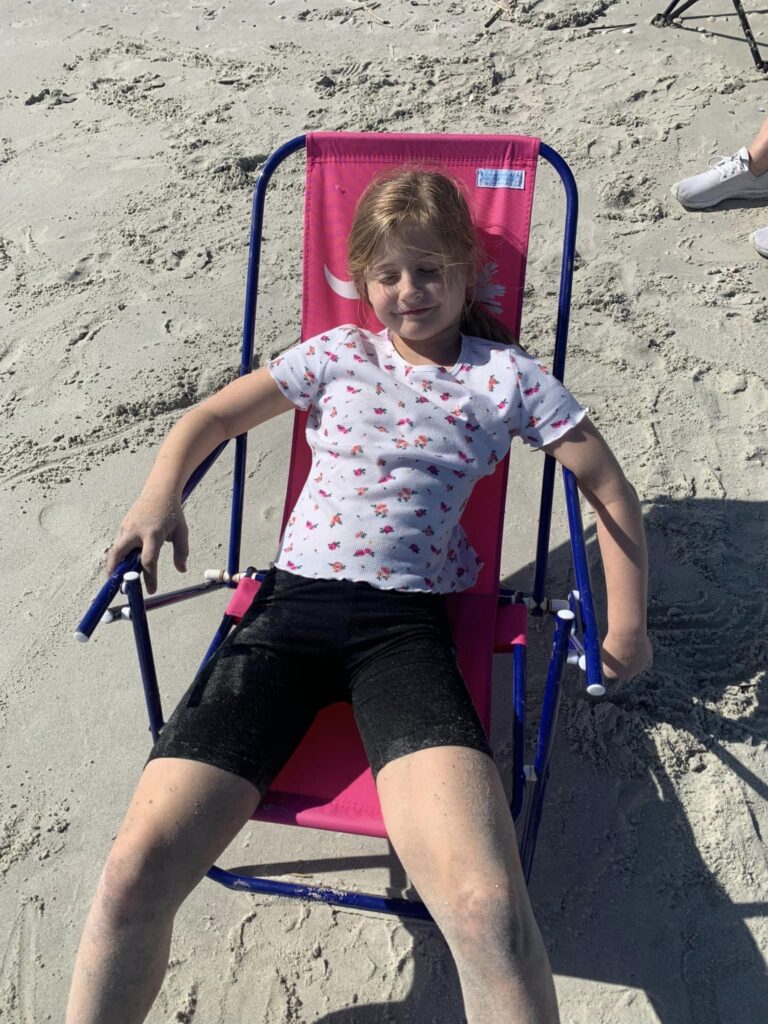 girl lounging in recliner chair on beach