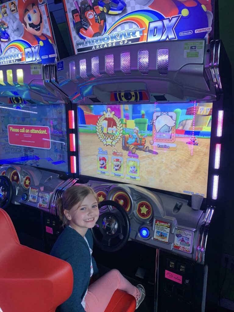 girl smiling in front of arcade game